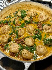 meatballs in braised with creamy sauce and spinach on top of wooden board