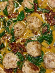 close up of meatballs and spinach in cream sauce